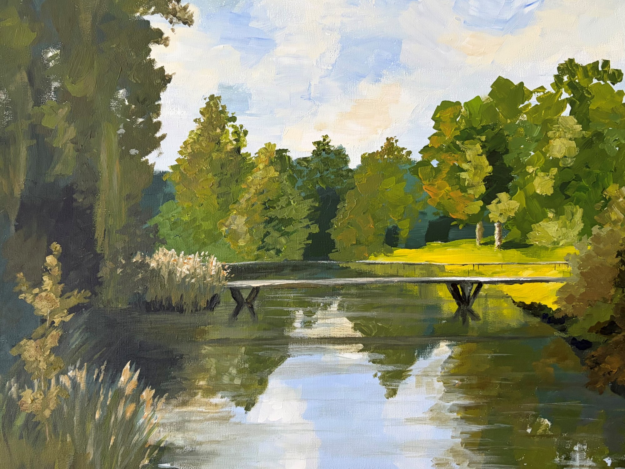 Impressionistic landscape painting of a small footbridge crossing a narrow waterway in a lush green setting. Sunlit grass and trees are reflected in the calm water beneath the bridge.