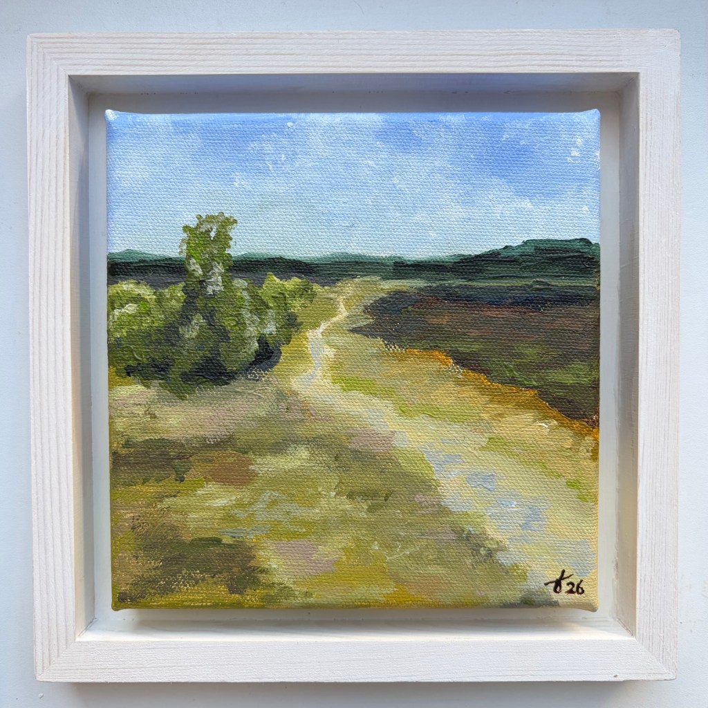 Miniature acrylic painting of a sandy path winding through green and brown heathland, with trees beneath a pale blue sky, in a white wooden floating frame.
