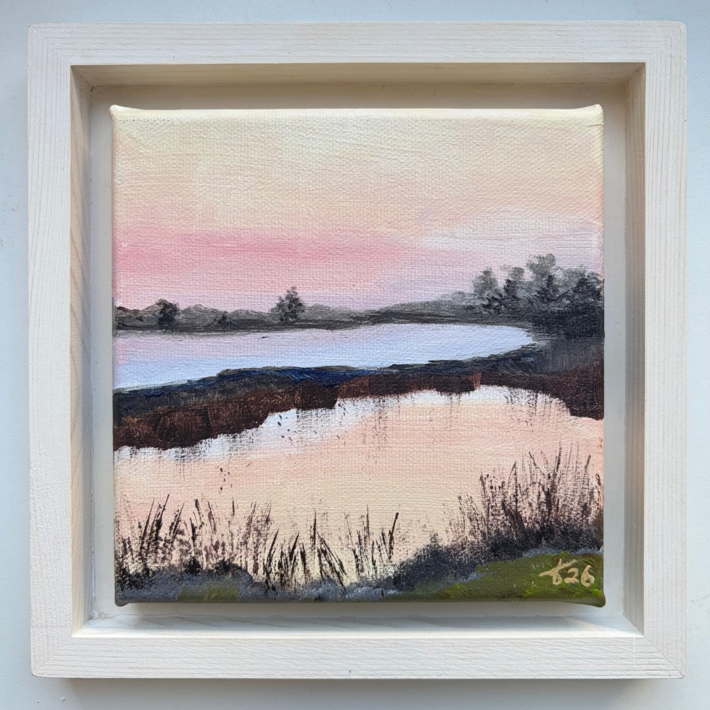 Miniature acrylic painting of calm water reflecting a pink and peach evening sky, with dark grasses and trees along the banks, in a white wooden floating frame.
