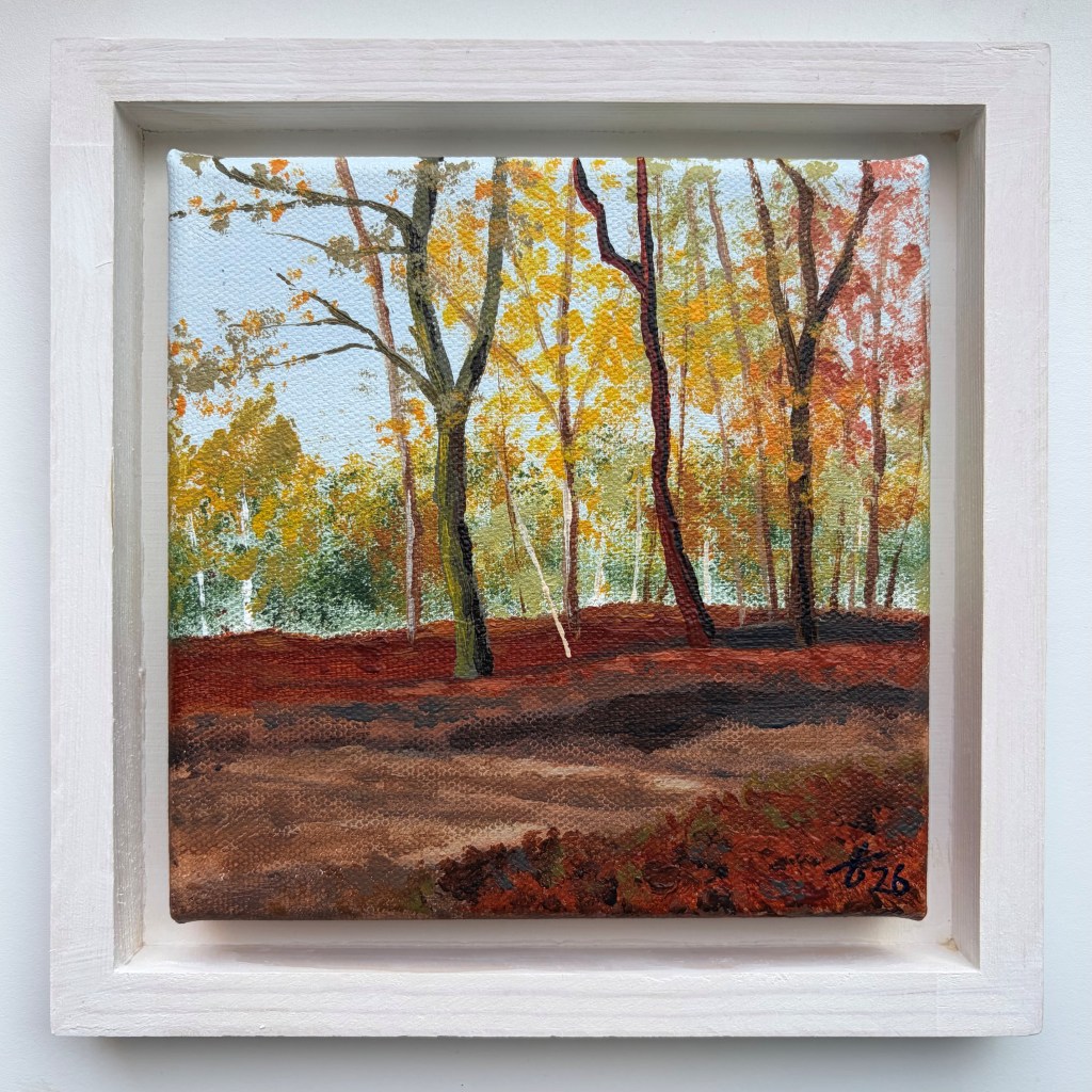 Miniature acrylic painting of an autumn forest with tall dark tree trunks, golden yellow and orange foliage and a reddish-brown woodland floor, in a white wooden floating frame.